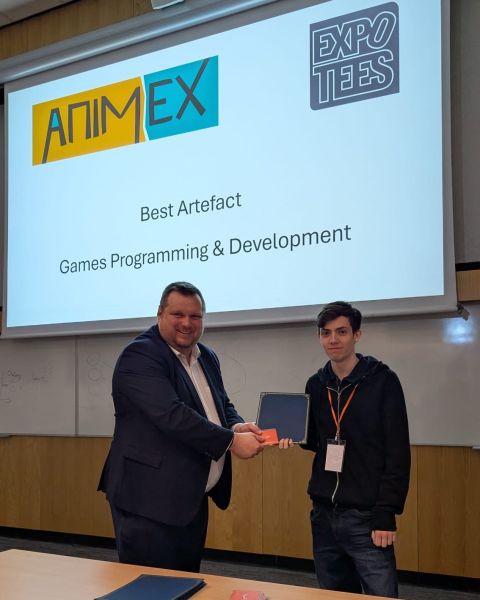 Oliver Neal collecting the Best Artefact award for Games Programming and Development at ExpoTees 2026, in front of a screen reading Best Artefact, Games Programming & Development